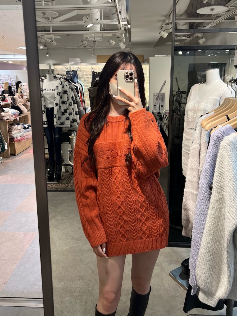 オレンジ系のニット/セーター、ブラック系のブーツを着用したレディースの冬コーディネートの2枚目の写真