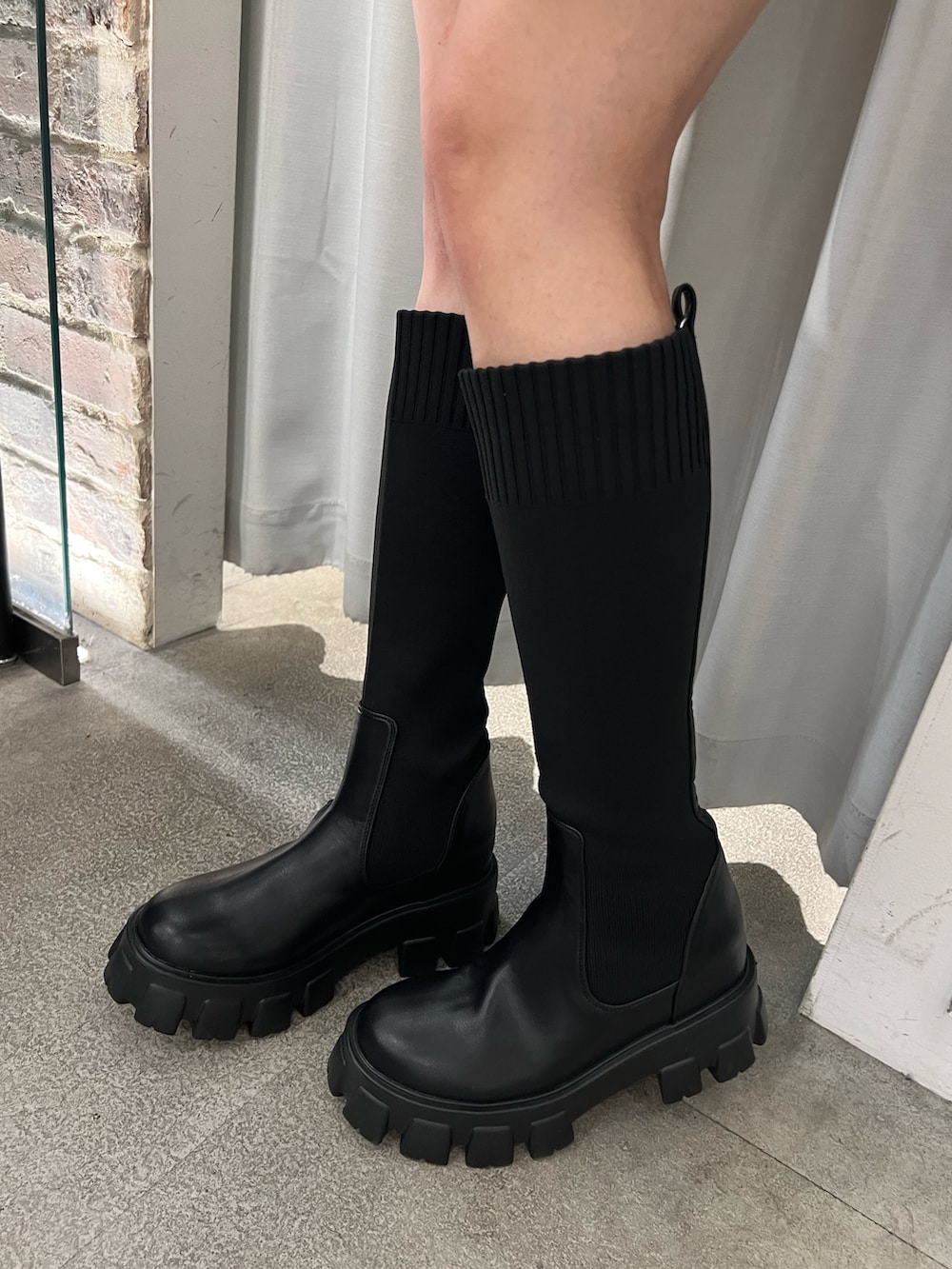 ブラック系のワンピース、ブラック系のブーツを着用したレディースの秋コーディネートの5枚目の写真