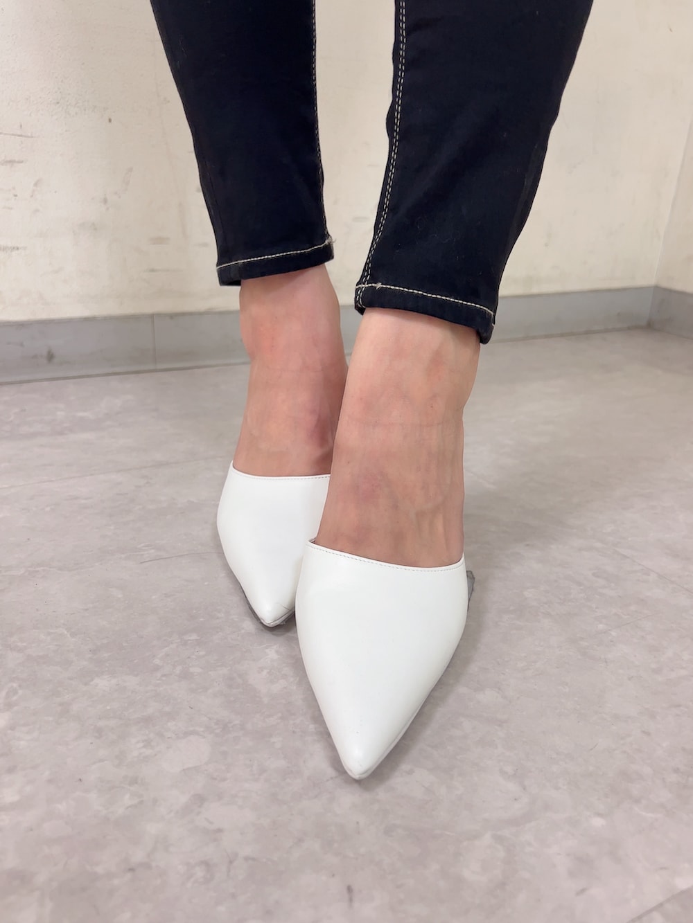 グレー系のニット/セーター、ブラック系のデニムパンツ、ホワイト系のパンプスを着用したレディースの秋コーディネートの6枚目の写真