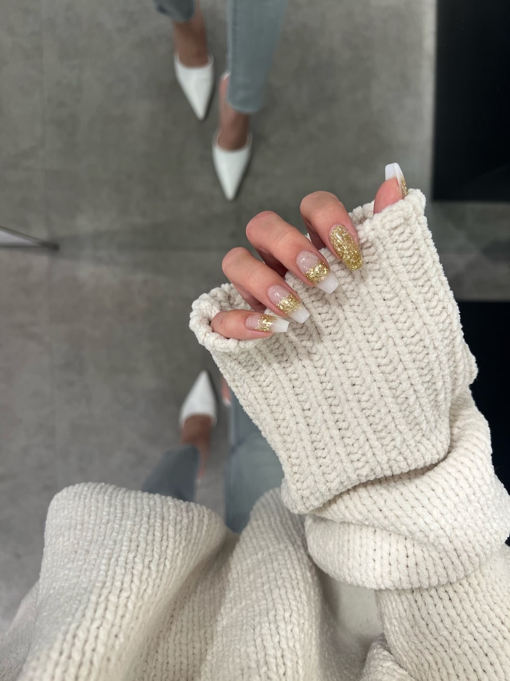 ホワイト系のニット/セーター、ブルー系のデニムパンツ、ホワイト系のハンドバッグを着用したレディースの冬コーディネートの4枚目の写真