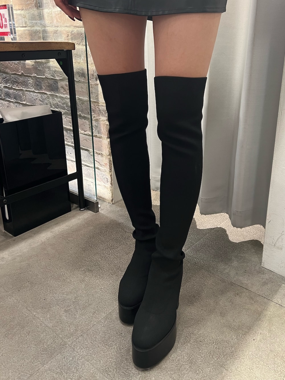 ピンク系のスウェット、ブラック系のスカート、ブラック系のブーツを着用したレディースの冬コーディネートの6枚目の写真