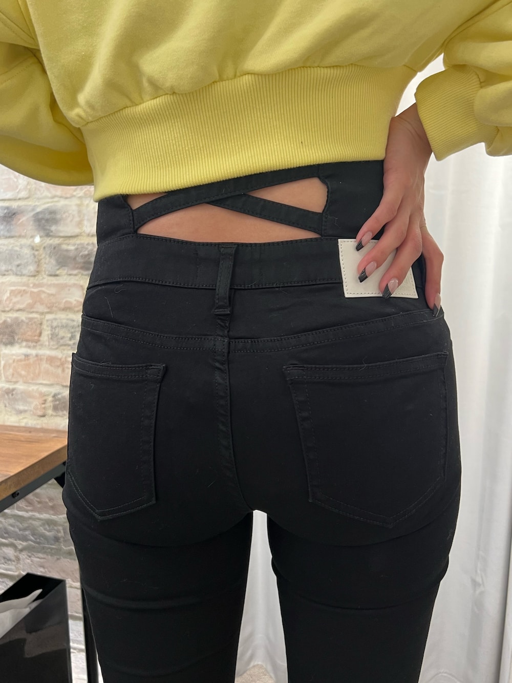 イエロー系のスウェット、ブラック系のデニムパンツ、ブラック系のパンプスを着用したレディースの冬コーディネートの6枚目の写真