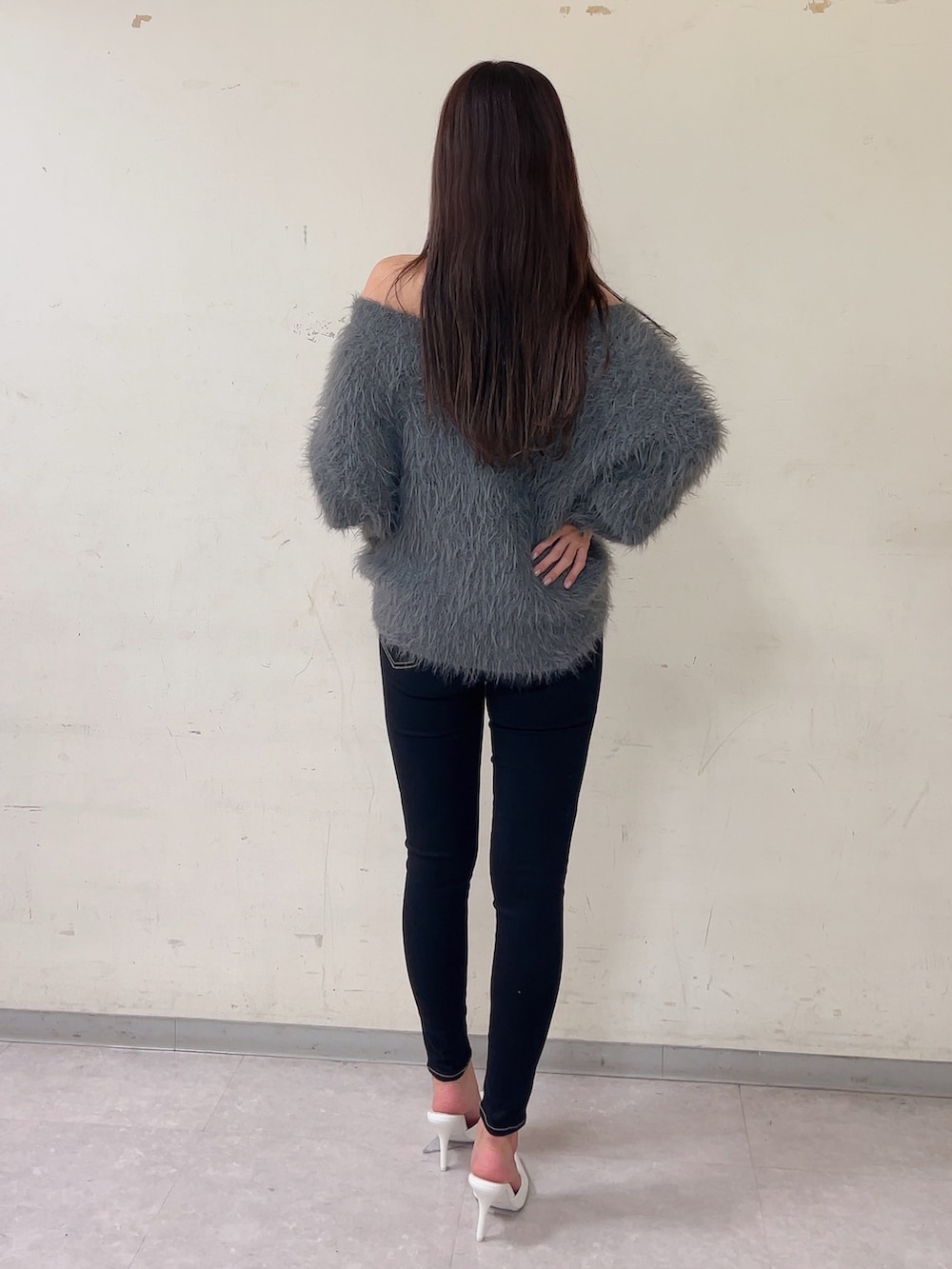 グレー系のニット/セーター、ブラック系のデニムパンツ、ホワイト系のパンプスを着用したレディースの秋コーディネートの2枚目の写真