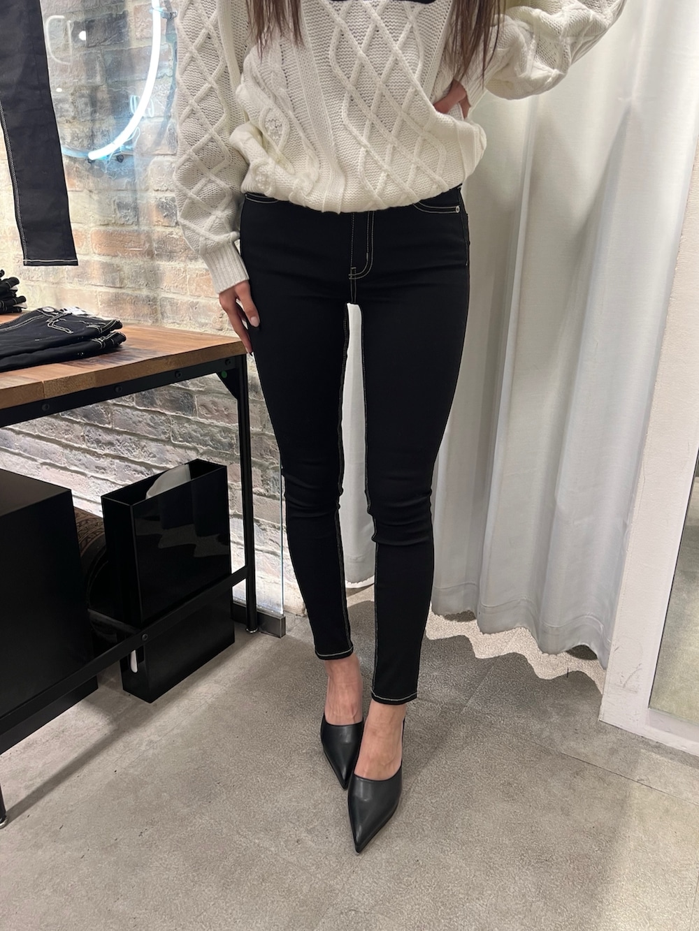 ホワイト系のニット/セーター、ブラック系のデニムパンツ、ブラック系のパンプスを着用したレディースの冬コーディネートの5枚目の写真