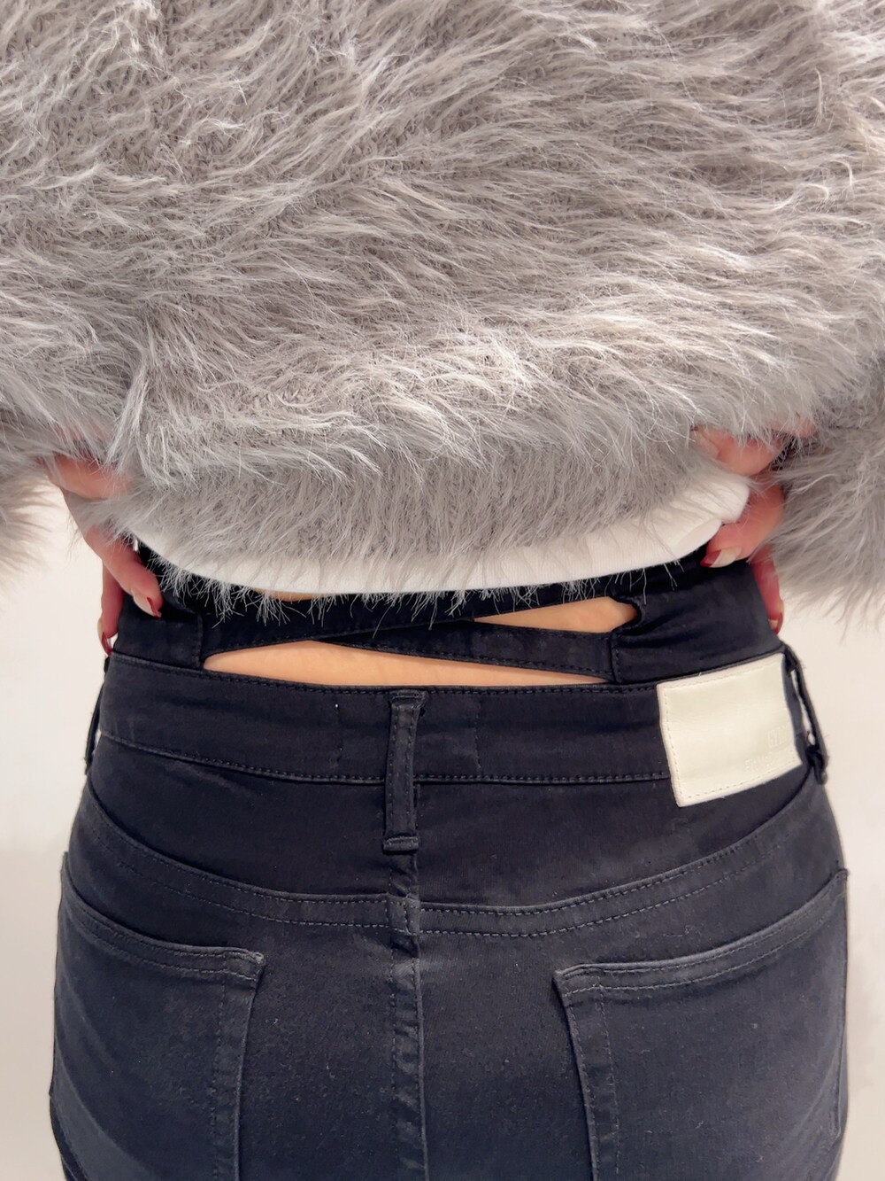 グレー系のカーディガン/ボレロ、ホワイト系のキャミソール、ブラック系のデニムパンツを着用したレディースの秋コーディネートの6枚目の写真