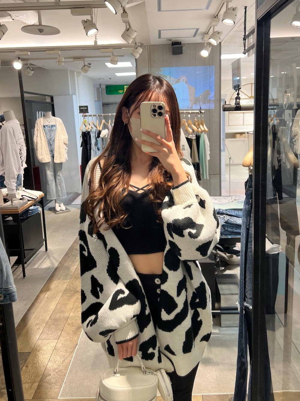 ブラック系のキャミソール、ブラック系のデニムパンツ、ホワイト系のパンプスを着用したレディースの春コーディネートの2枚目の写真