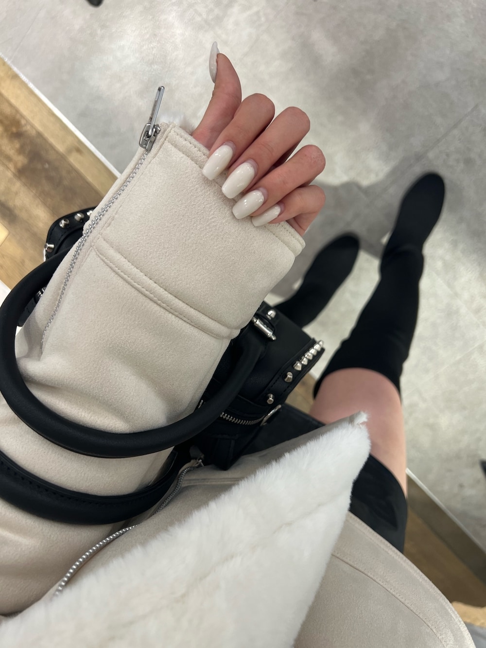 ホワイト系のムートンコート、ホワイト系のニット/セーター、ブラック系のスカートを着用したレディースの秋コーディネートの3枚目の写真