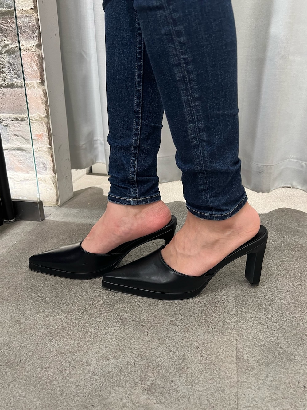 グレー系のスウェット、ブルー系のデニムパンツ、ブラック系のパンプスを着用したレディースの冬コーディネートの5枚目の写真