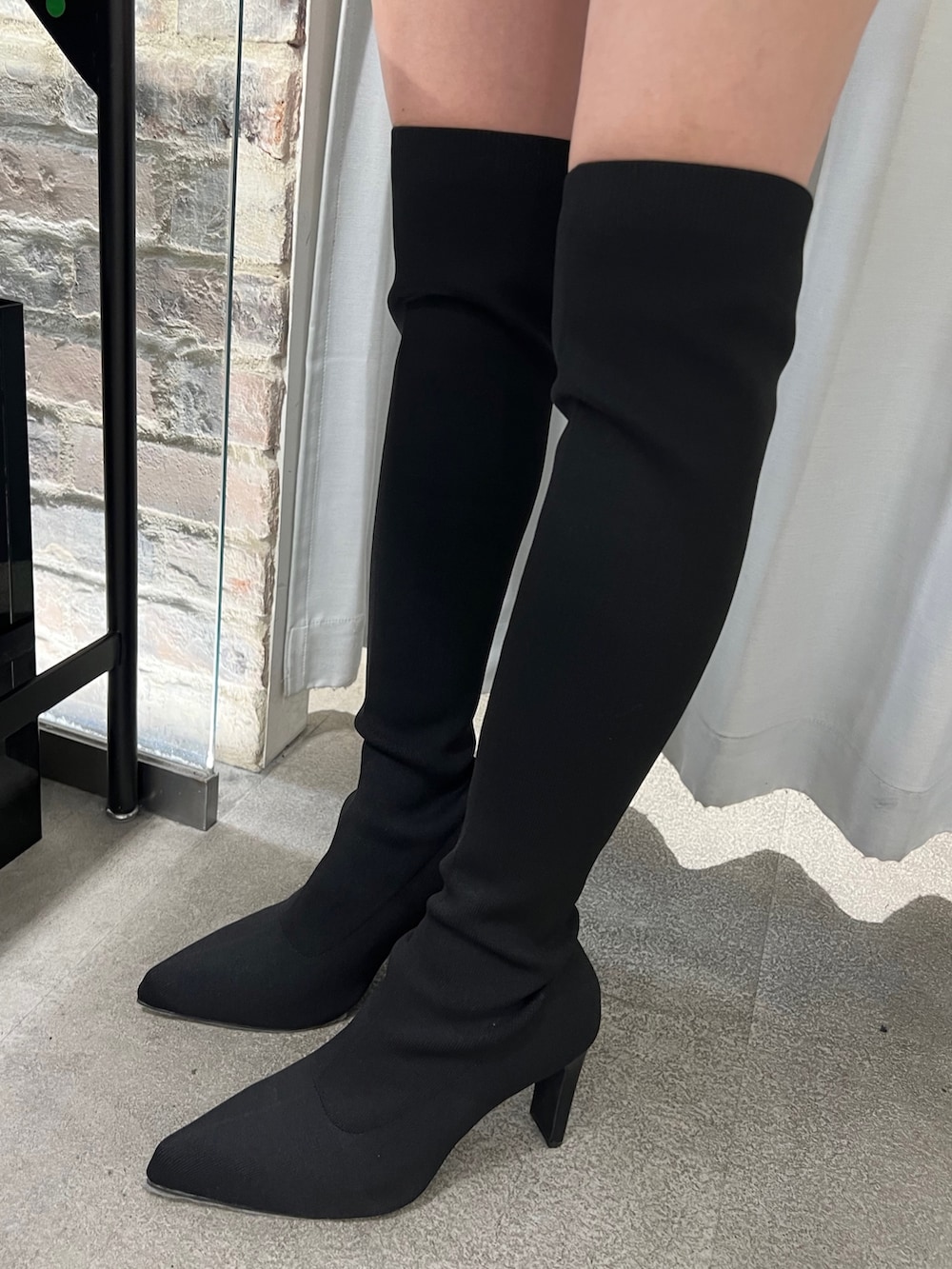 ブラック系のニット/セーター、ホワイト系のハンドバッグ、ブラック系のデニムパンツを着用したレディースの秋コーディネートの5枚目の写真