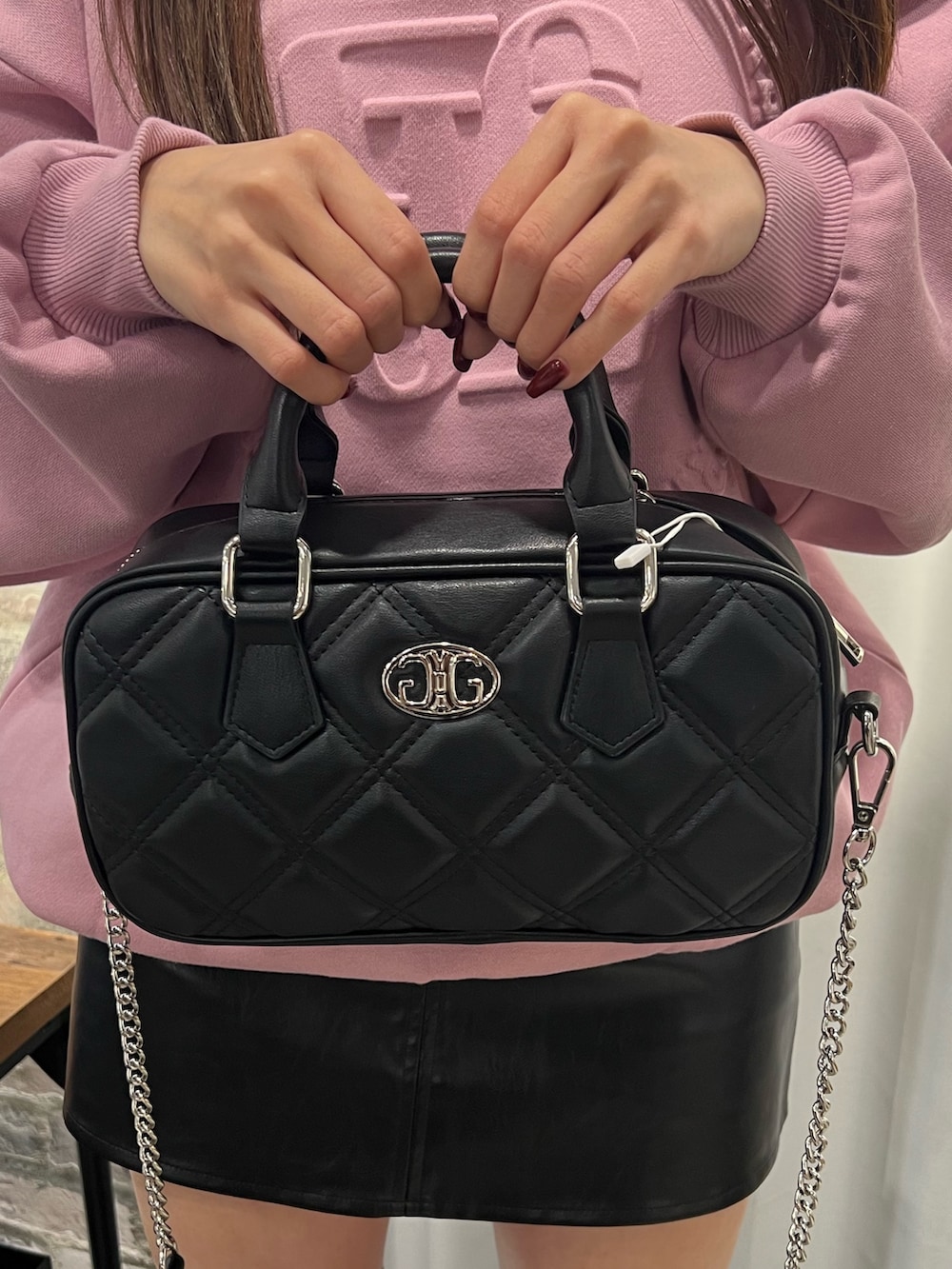 ピンク系のスウェット、ブラック系のスカート、ブラック系のブーツを着用したレディースの冬コーディネートの7枚目の写真