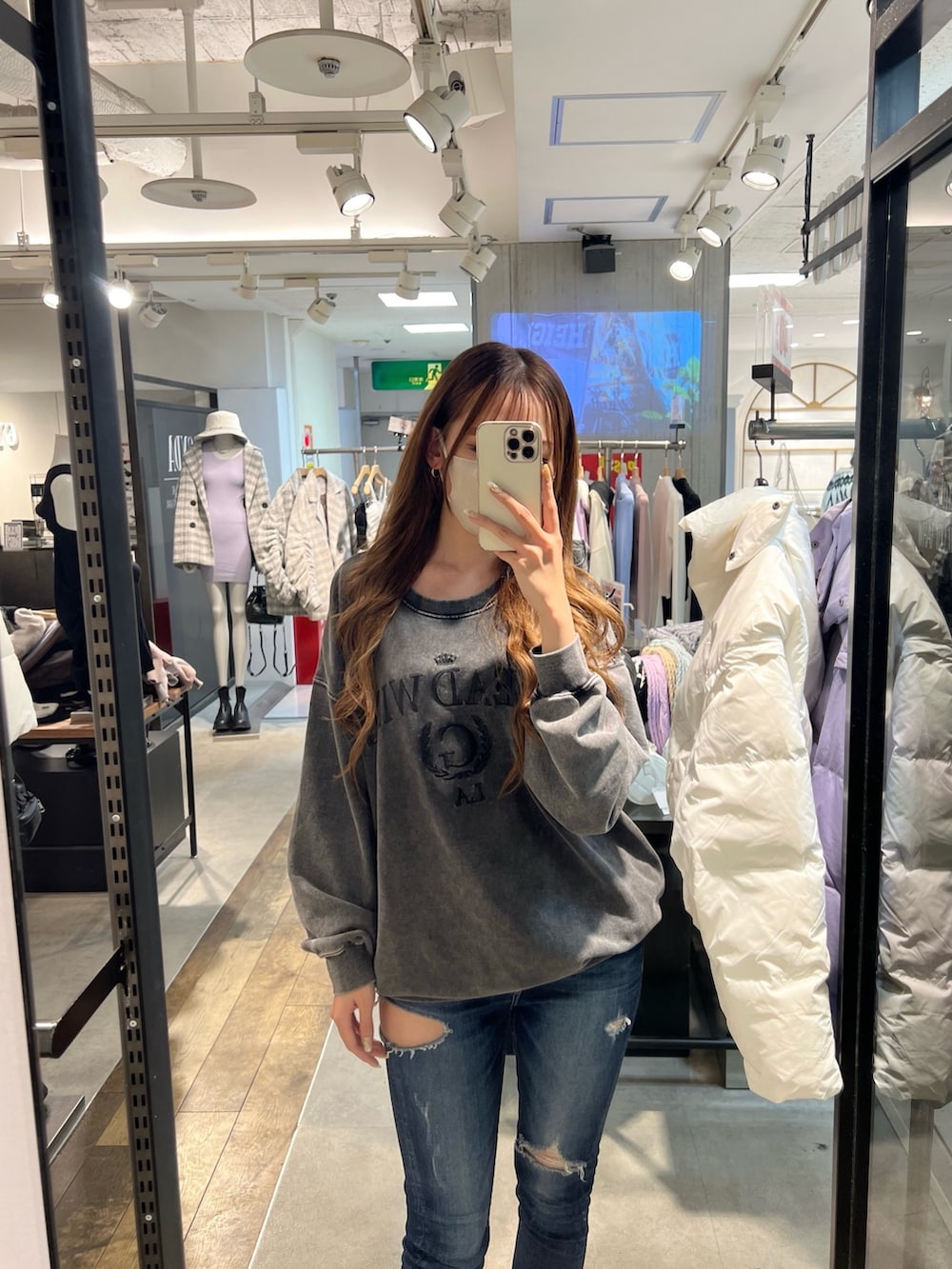 グレー系のスウェット、ブルー系のデニムパンツ、ブラック系のパンプスを着用したレディースの冬コーディネートの2枚目の写真