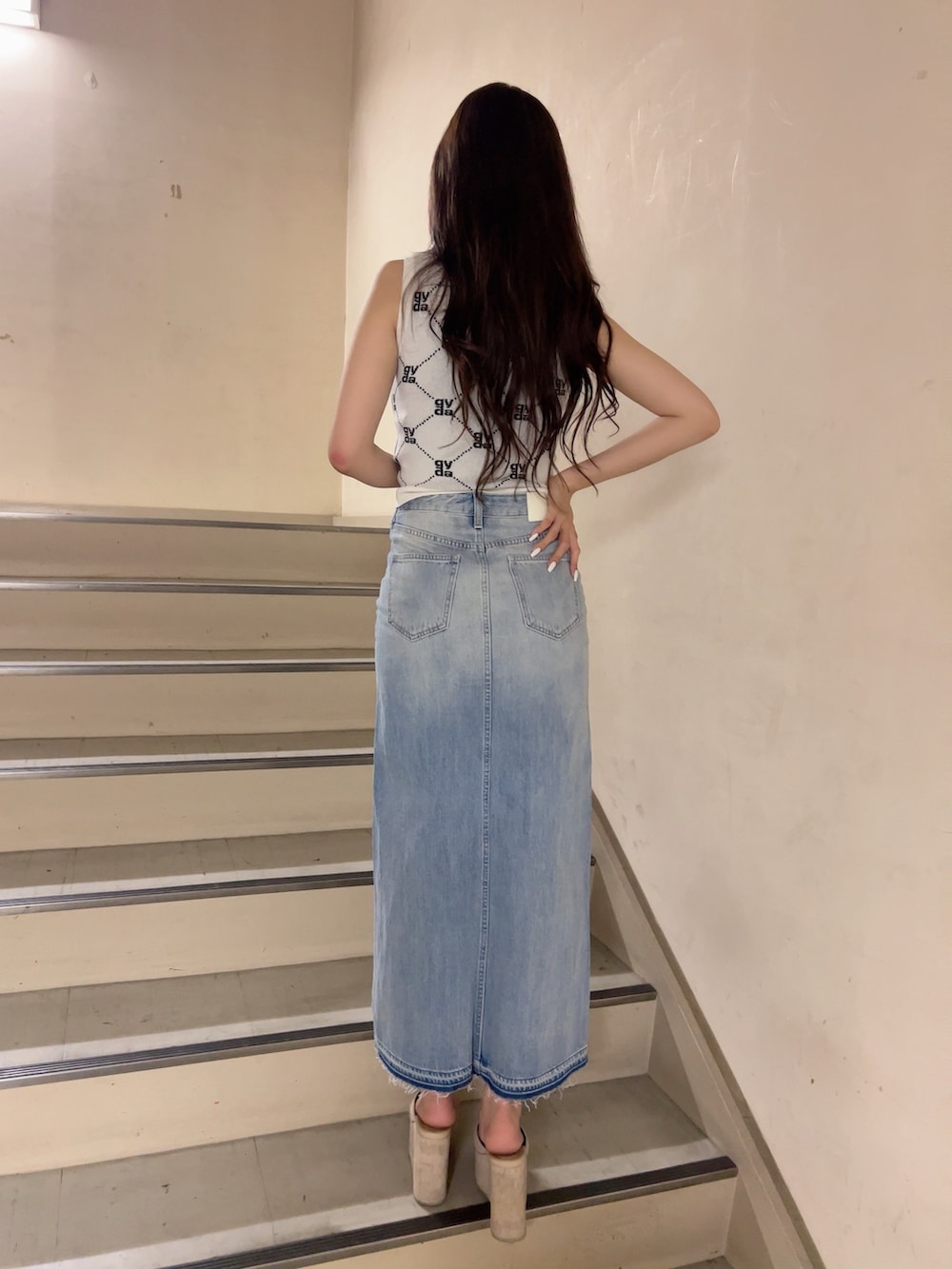 ホワイト系のニット/セーター、ブルー系のデニムスカート、ホワイト系のサンダルを着用したレディースの春コーディネートの2枚目の写真