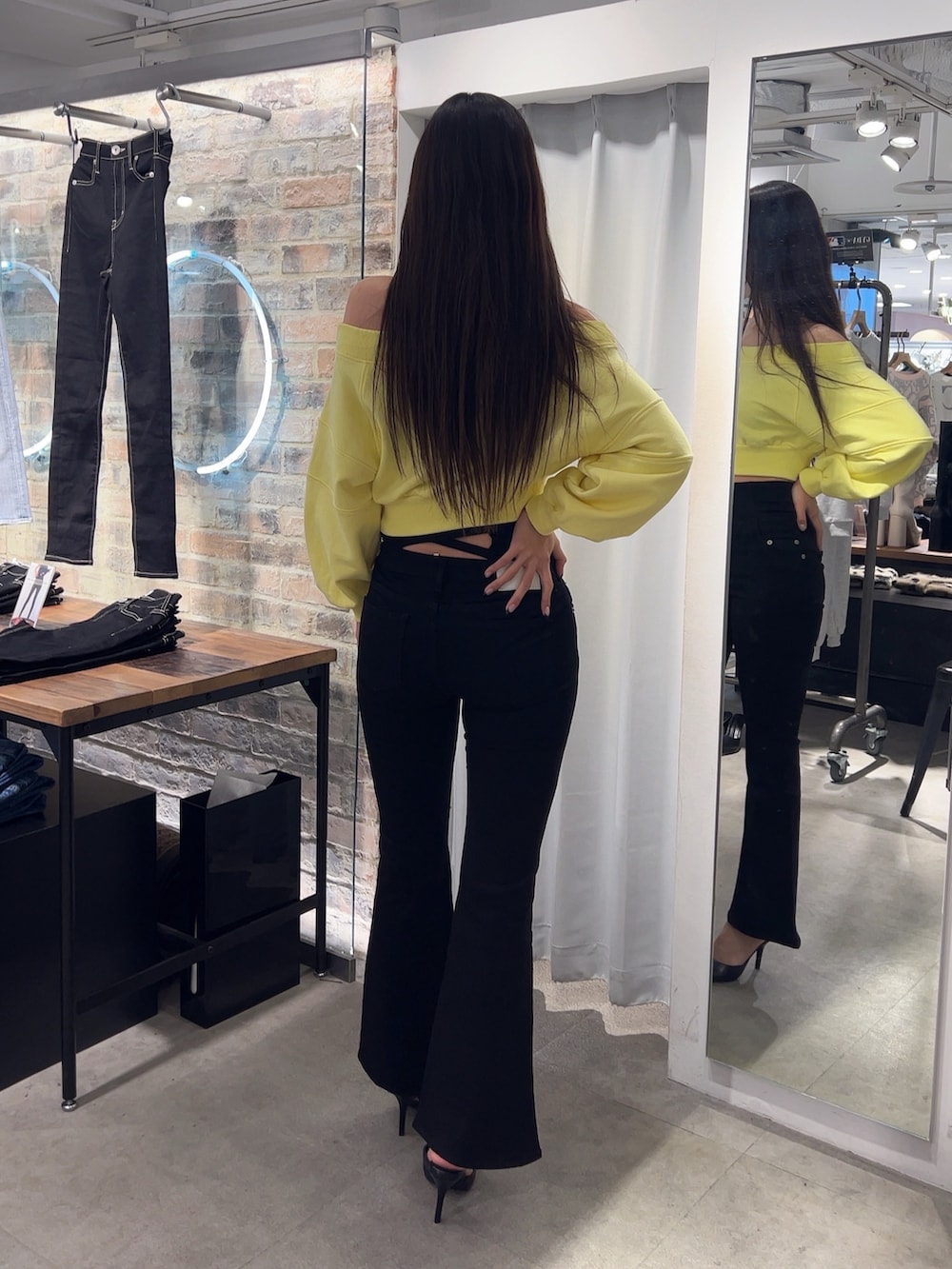 イエロー系のスウェット、ブラック系のデニムパンツ、ブラック系のパンプスを着用したレディースの冬コーディネートの2枚目の写真