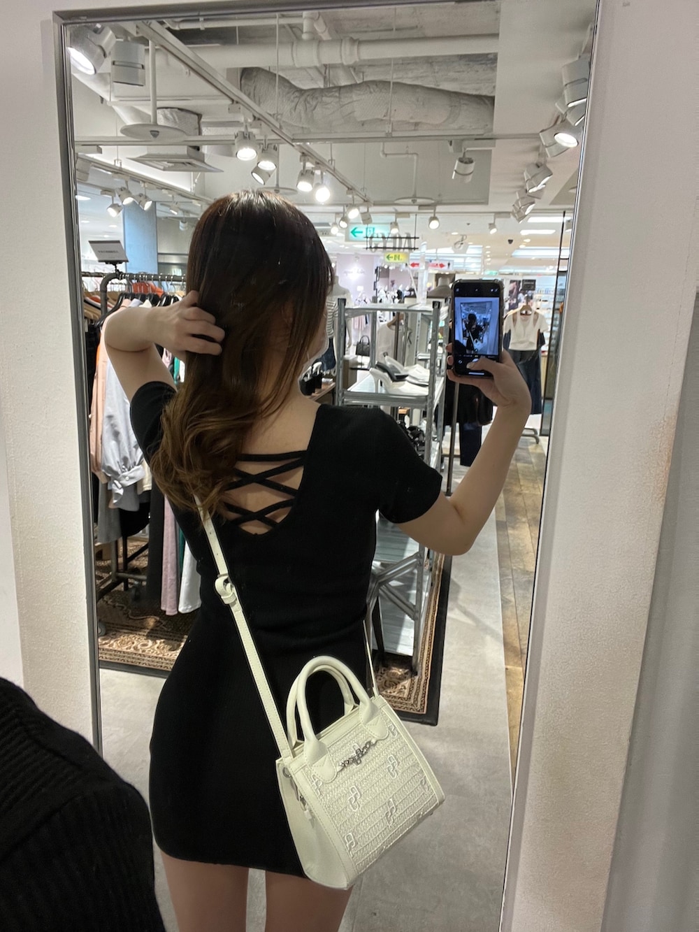 ブラック系のワンピース、ホワイト系のハンドバッグ、ブラック系のサンダルを着用したレディースの春コーディネートの4枚目の写真