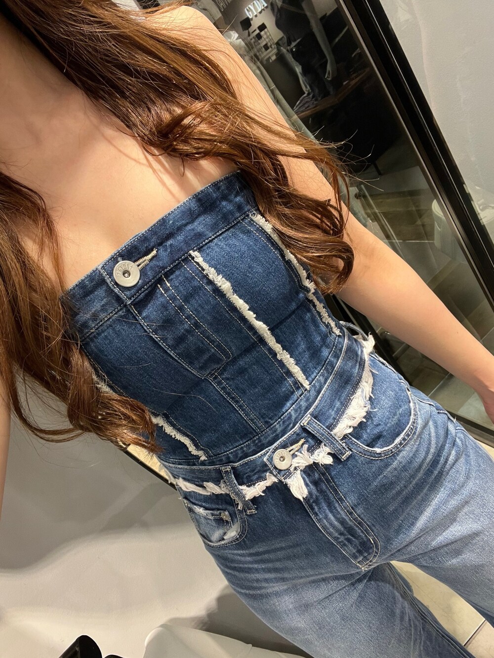 ブルー系のチューブトップ、ブルー系のデニムパンツ、ホワイト系のハンドバッグを着用したレディースの春コーディネートの3枚目の写真