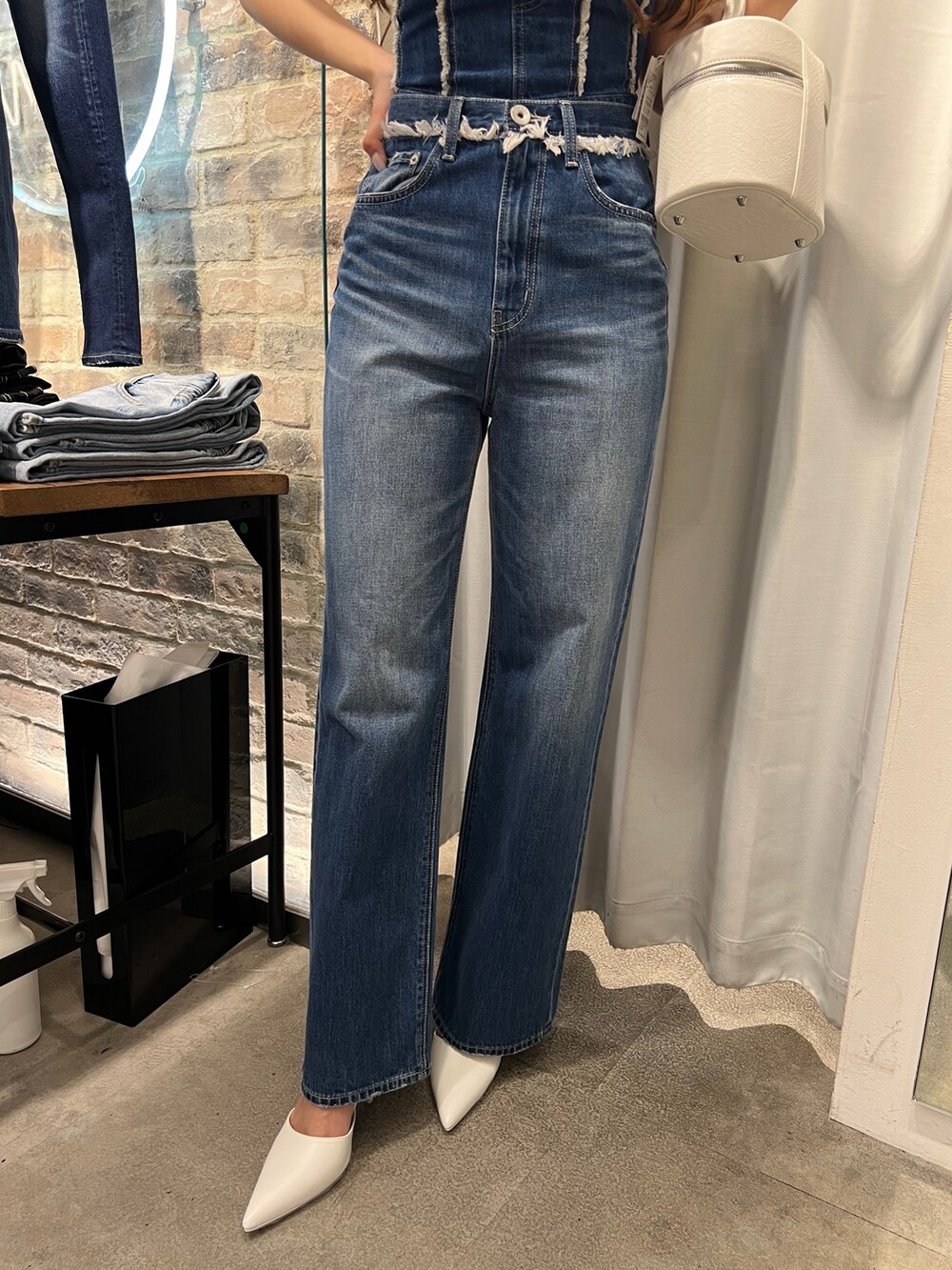 ブルー系のチューブトップ、ブルー系のデニムパンツ、ホワイト系のハンドバッグを着用したレディースの春コーディネートの4枚目の写真