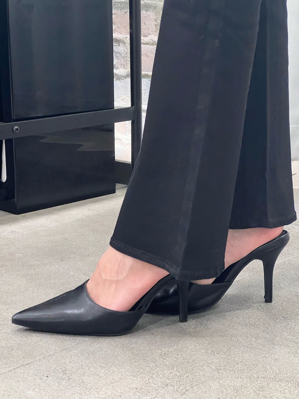 イエロー系のスウェット、ブラック系のデニムパンツ、ブラック系のパンプスを着用したレディースの冬コーディネートの7枚目の写真