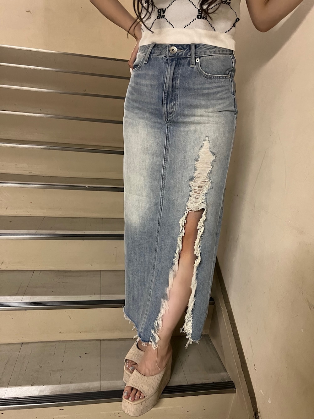 ホワイト系のニット/セーター、ブルー系のデニムスカート、ホワイト系のサンダルを着用したレディースの春コーディネートの5枚目の写真