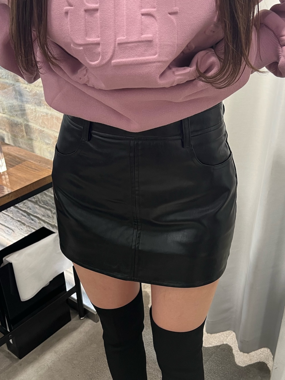 ピンク系のスウェット、ブラック系のスカート、ブラック系のブーツを着用したレディースの冬コーディネートの5枚目の写真