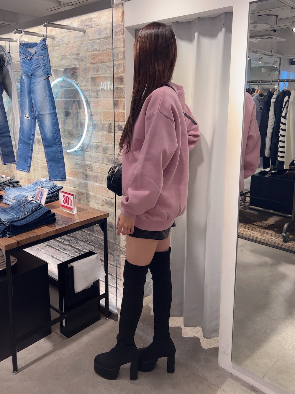 ピンク系のスウェット、ブラック系のスカート、ブラック系のブーツを着用したレディースの冬コーディネートの3枚目の写真