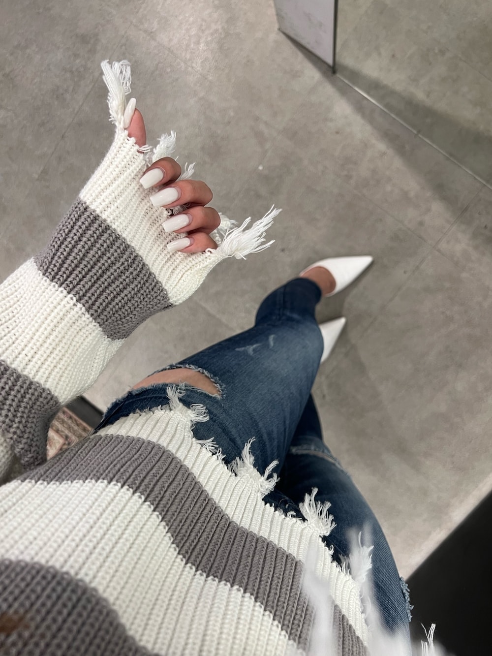グレー系のニット/セーター、ブルー系のデニムパンツ、ホワイト系のパンプスを着用したレディースの夏コーディネートの6枚目の写真