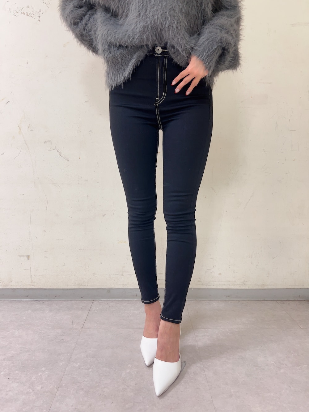 グレー系のニット/セーター、ブラック系のデニムパンツ、ホワイト系のパンプスを着用したレディースの秋コーディネートの5枚目の写真