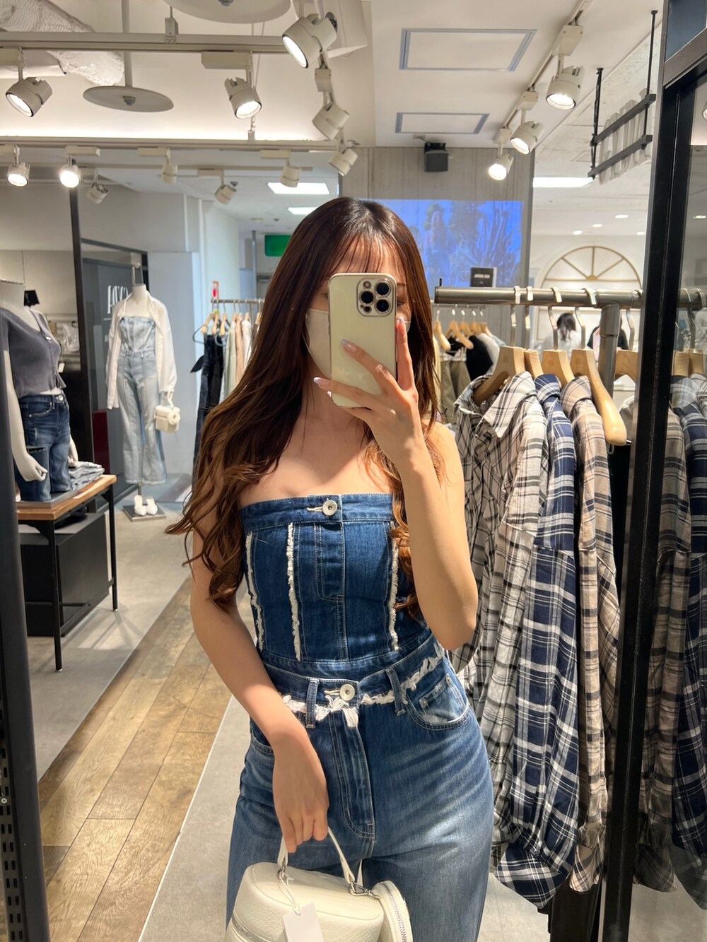 ブルー系のチューブトップ、ブルー系のデニムパンツ、ホワイト系のハンドバッグを着用したレディースの春コーディネートの2枚目の写真