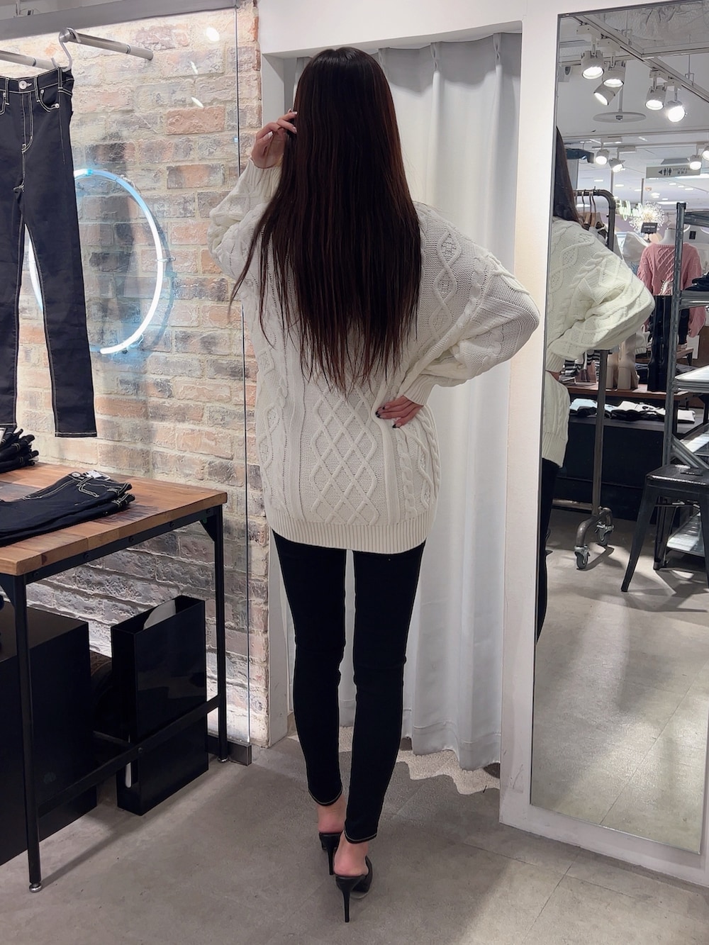 ホワイト系のニット/セーター、ブラック系のデニムパンツ、ブラック系のパンプスを着用したレディースの冬コーディネートの2枚目の写真