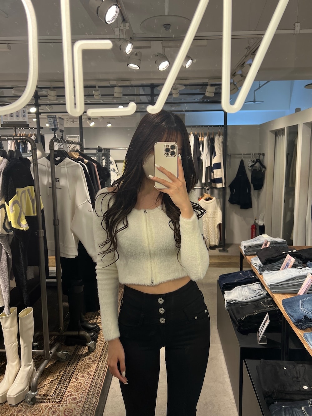 ホワイト系のニット/セーター、ブラック系のデニムパンツ、ホワイト系のパンプスを着用したレディースの冬コーディネートの2枚目の写真