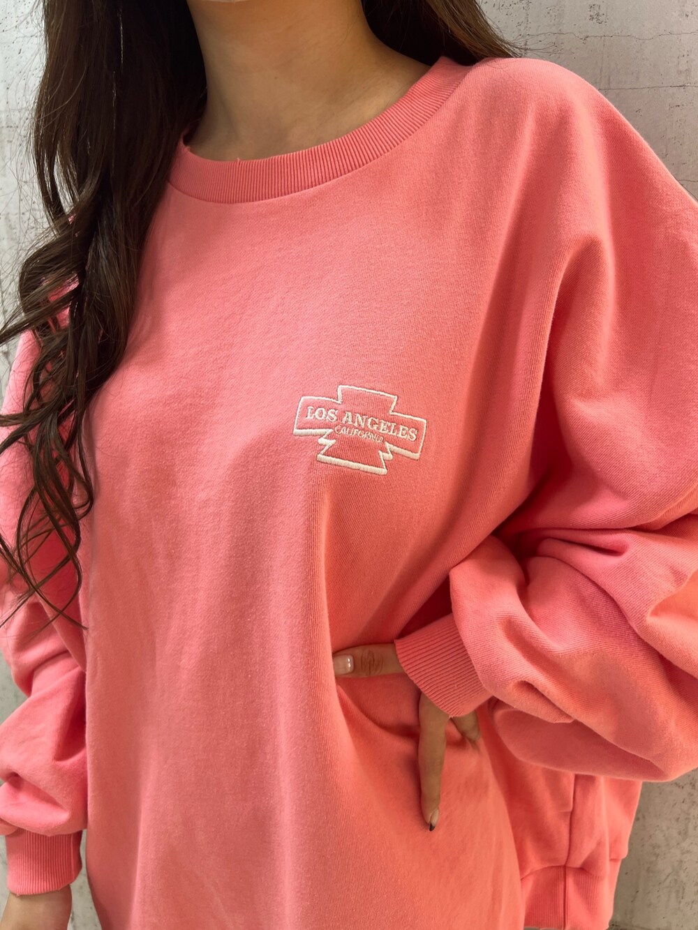 ピンク系のスウェット、ブルー系のデニムパンツ、ブラック系のパンプスを着用したレディースの冬コーディネートの3枚目の写真