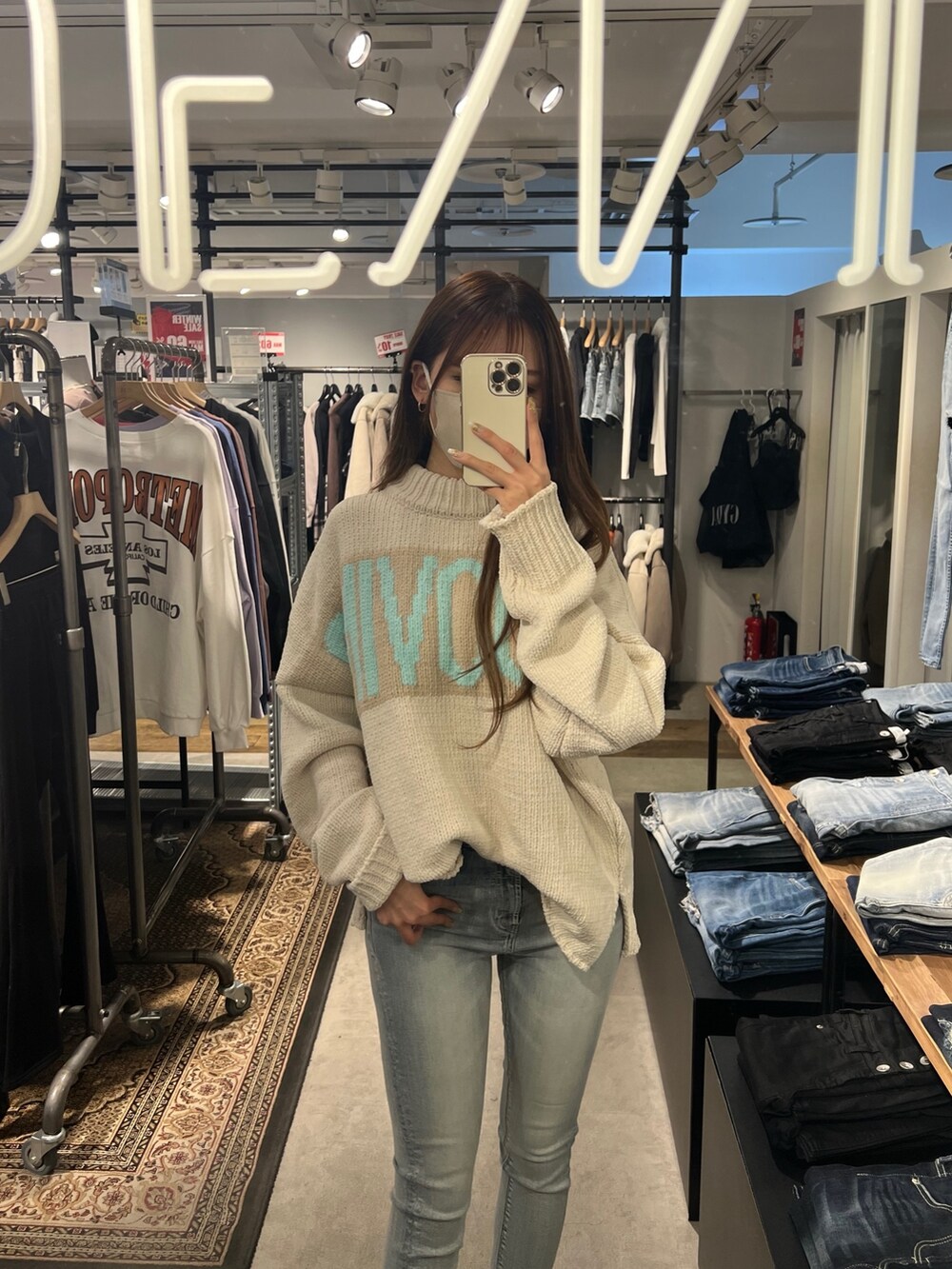 ホワイト系のニット/セーター、ブルー系のデニムパンツ、ホワイト系のハンドバッグを着用したレディースの冬コーディネートの2枚目の写真