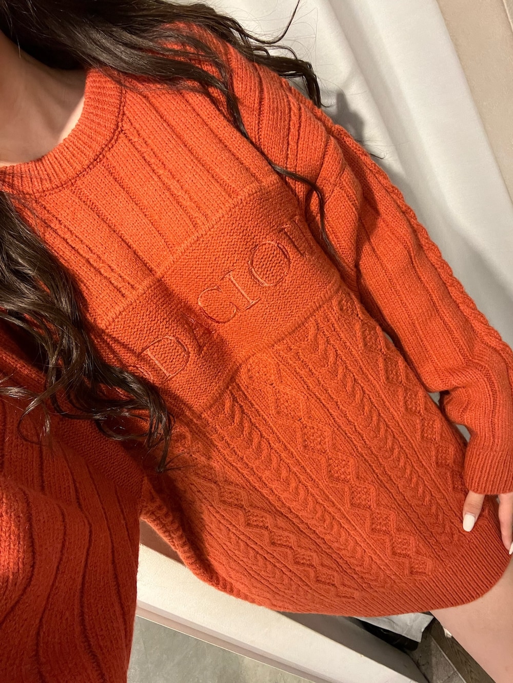 オレンジ系のニット/セーター、ブラック系のブーツを着用したレディースの冬コーディネートの3枚目の写真