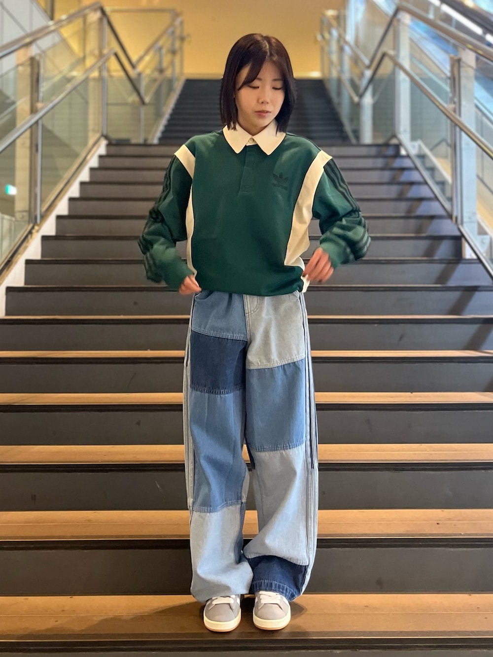 ブルー系のナイロンジャケット、グリーン系のポロシャツ、その他のデニムパンツを着用したレディースの春コーディネートの3枚目の写真