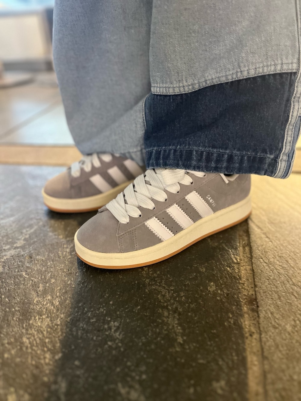 ブルー系のナイロンジャケット、グリーン系のポロシャツ、その他のデニムパンツを着用したレディースの春コーディネートの2枚目の写真