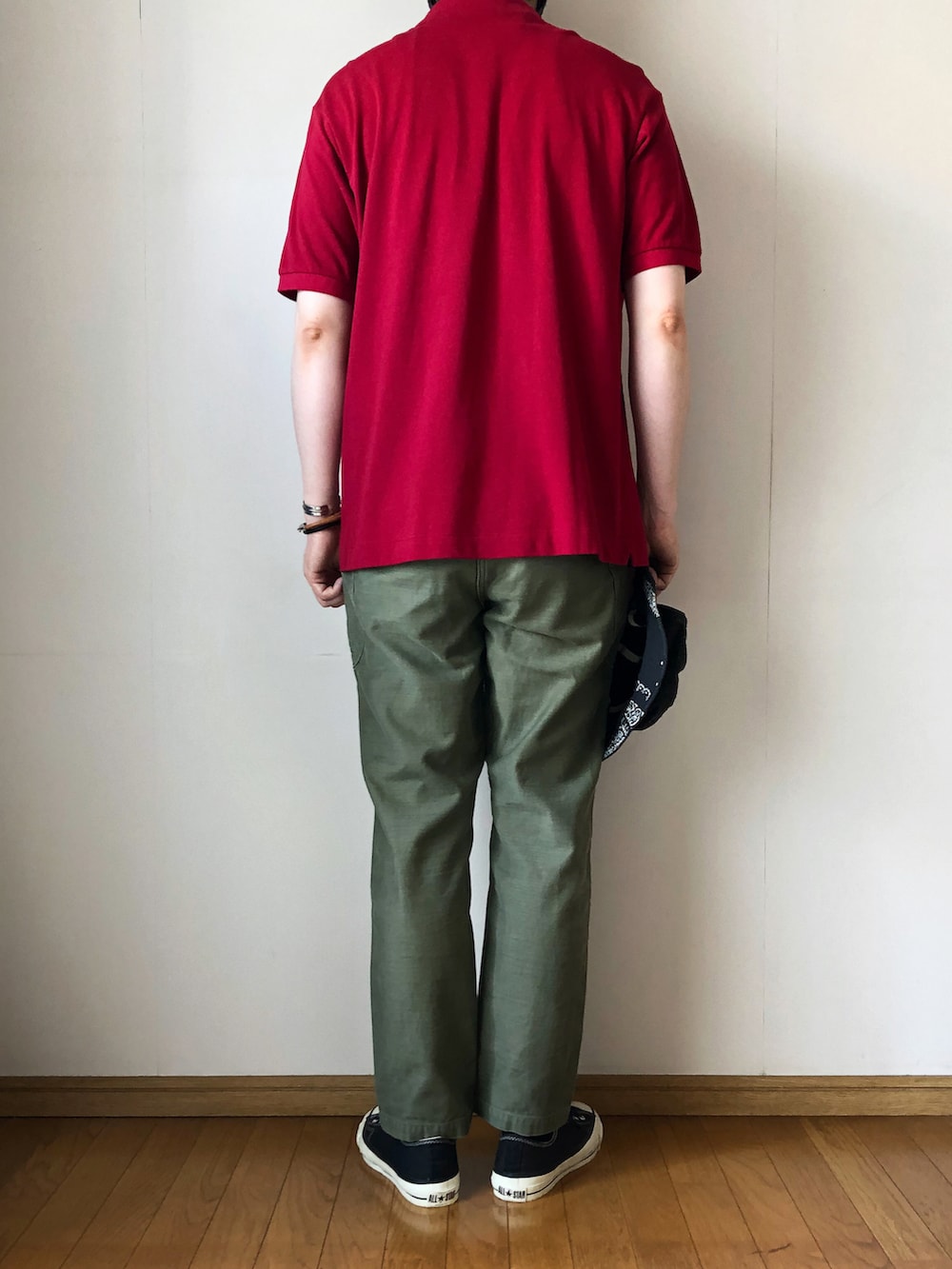 レッド系のポロシャツ、グリーン系のカーゴパンツ、ブラック系のスニーカーを着用したメンズの夏コーディネートの4枚目の写真