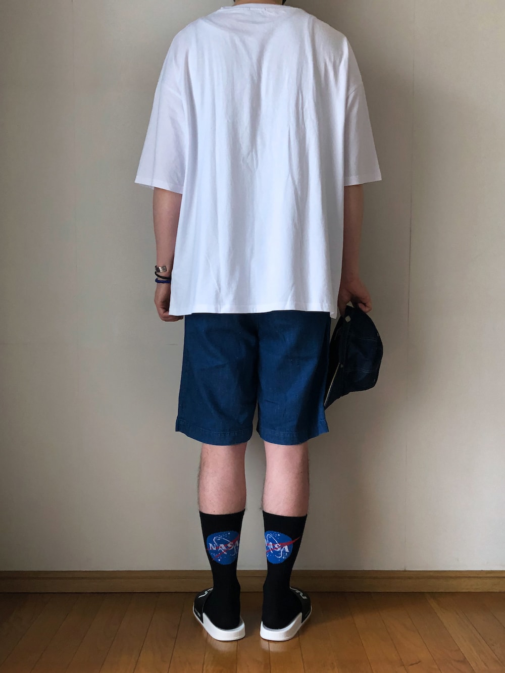 ホワイト系のTシャツ/カットソー、ブルー系のデニムパンツ、ブラック系のサンダルを着用したメンズの夏コーディネートの4枚目の写真