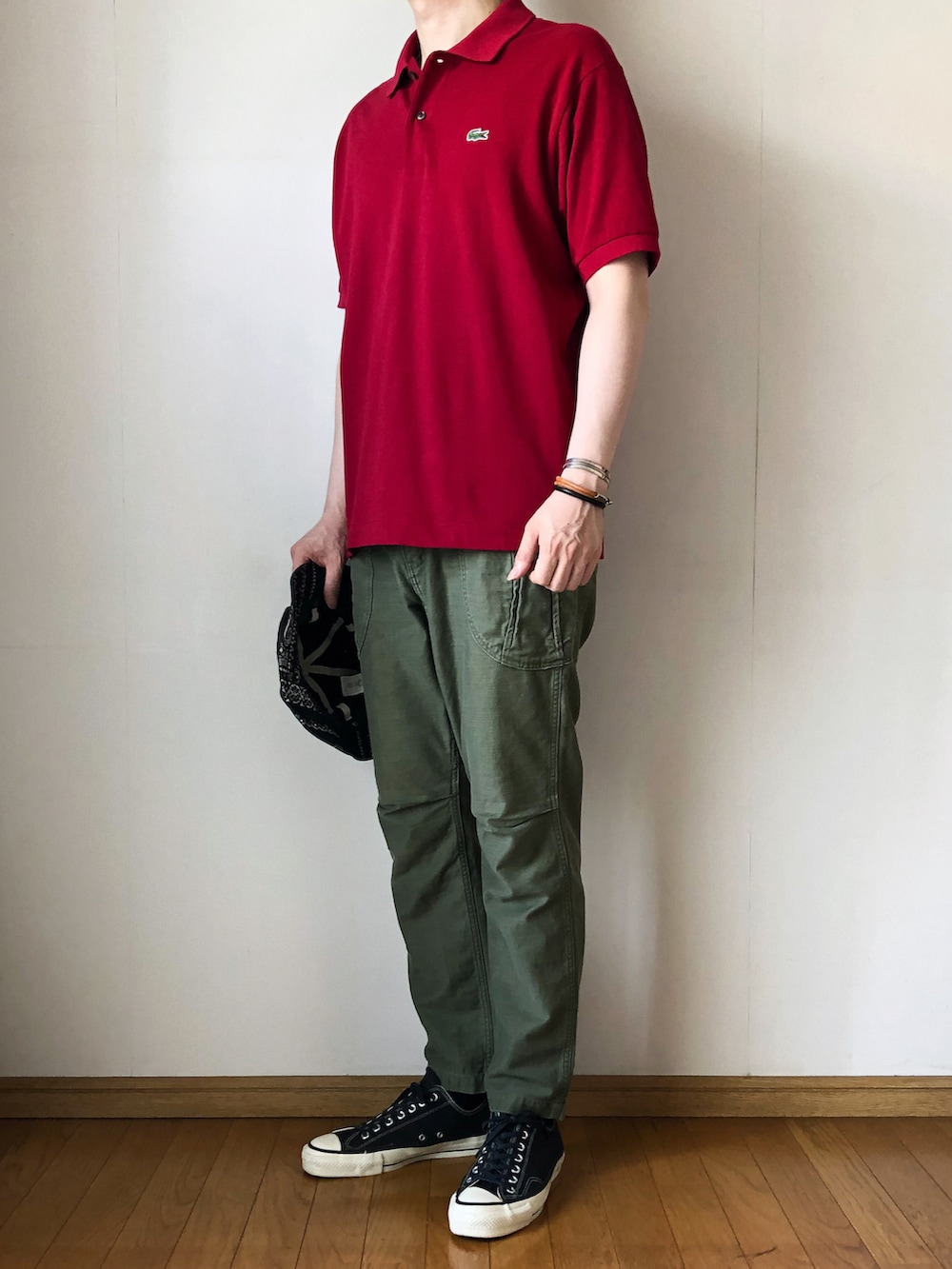 レッド系のポロシャツ、グリーン系のカーゴパンツ、ブラック系のスニーカーを着用したメンズの夏コーディネートの2枚目の写真