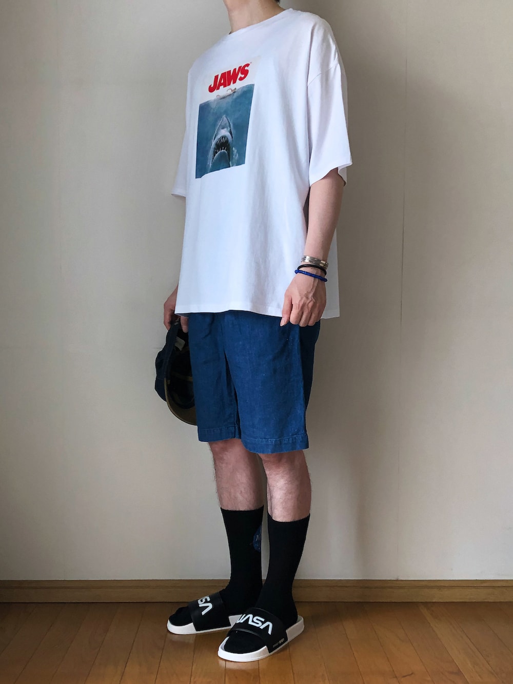 ホワイト系のTシャツ/カットソー、ブルー系のデニムパンツ、ブラック系のサンダルを着用したメンズの夏コーディネートの2枚目の写真