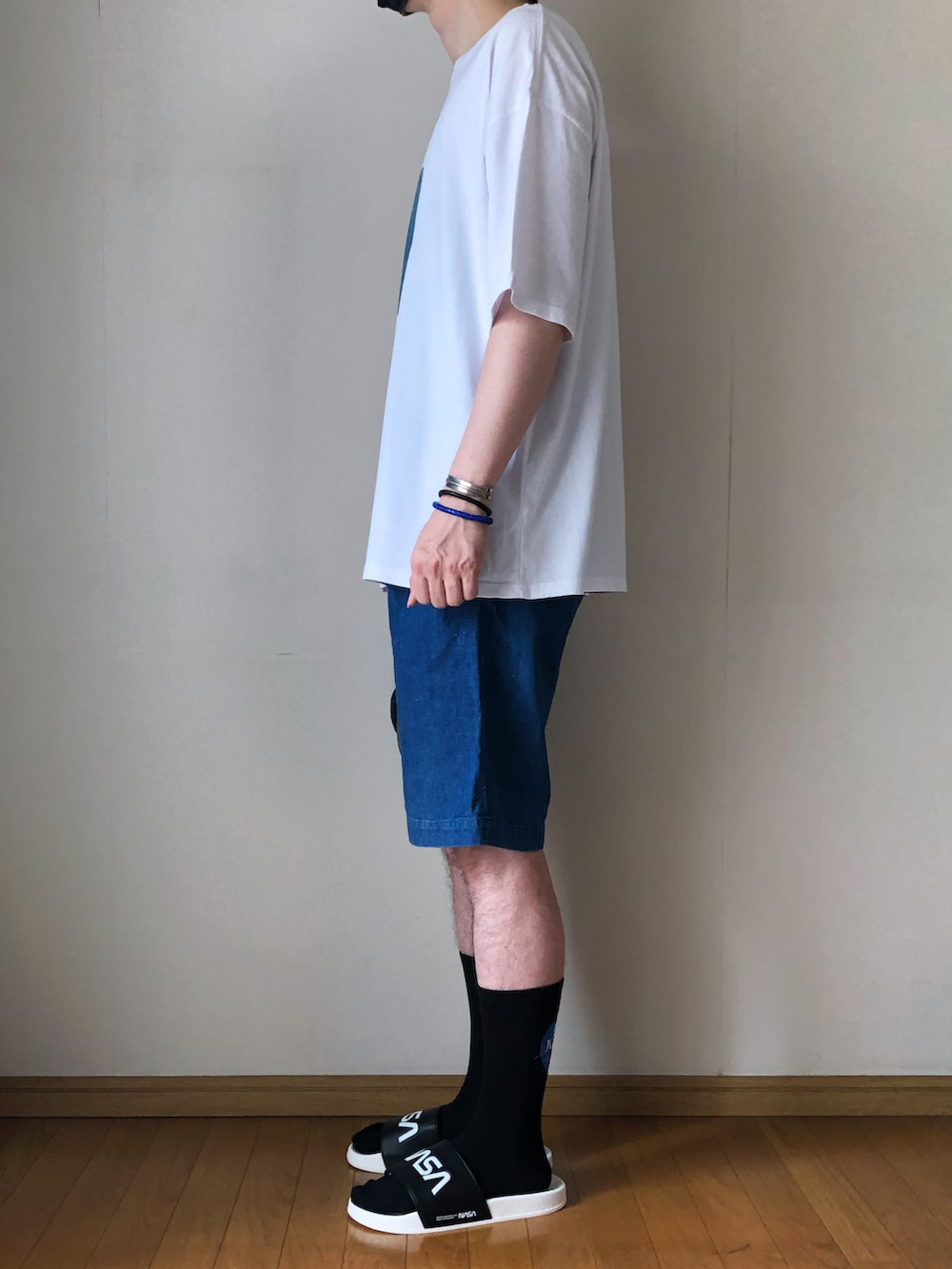 ホワイト系のTシャツ/カットソー、ブルー系のデニムパンツ、ブラック系のサンダルを着用したメンズの夏コーディネートの3枚目の写真