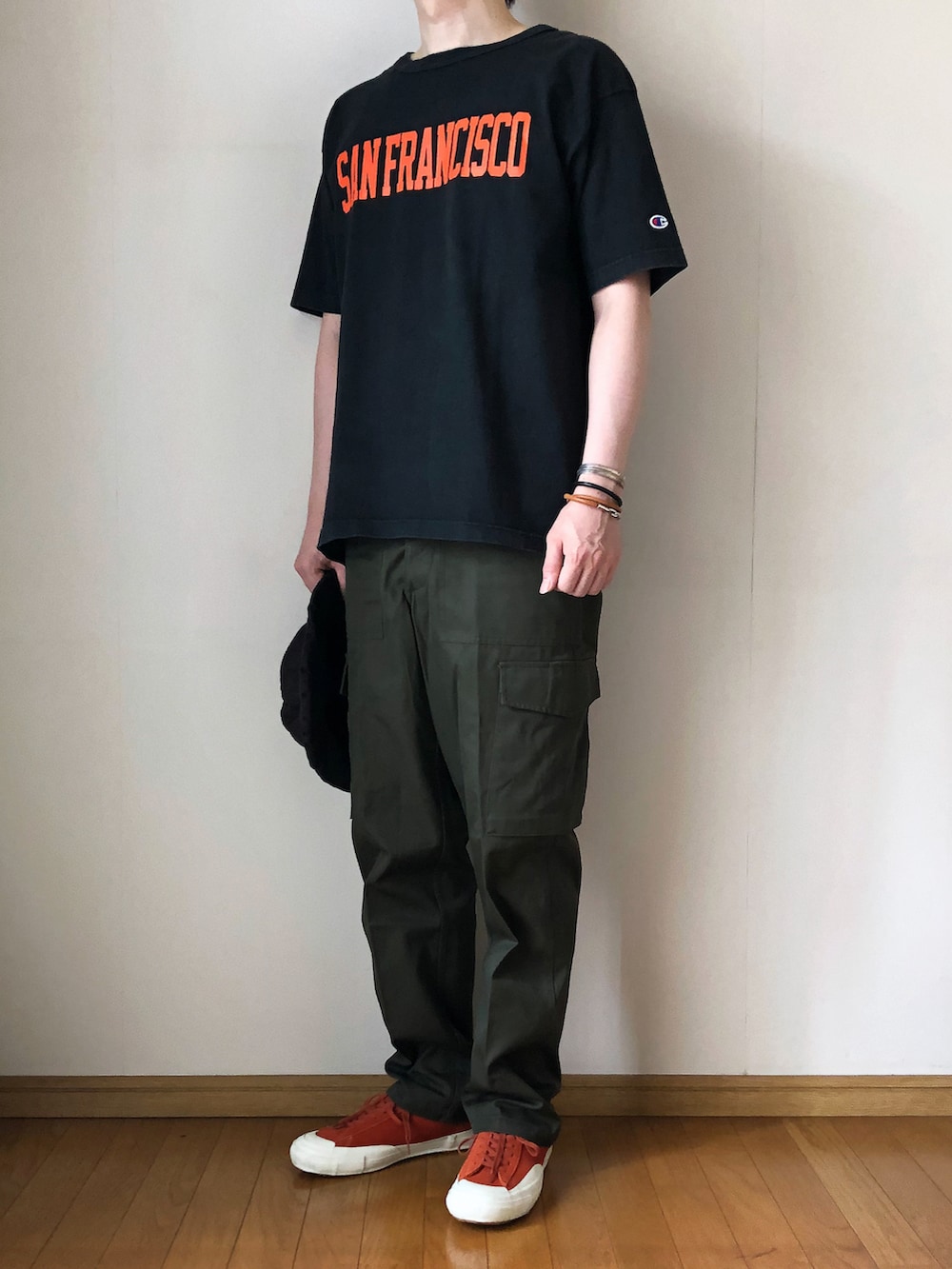 ブラック系のTシャツ/カットソー、グリーン系のカーゴパンツ、オレンジ系のスニーカーを着用したメンズの夏コーディネートの2枚目の写真