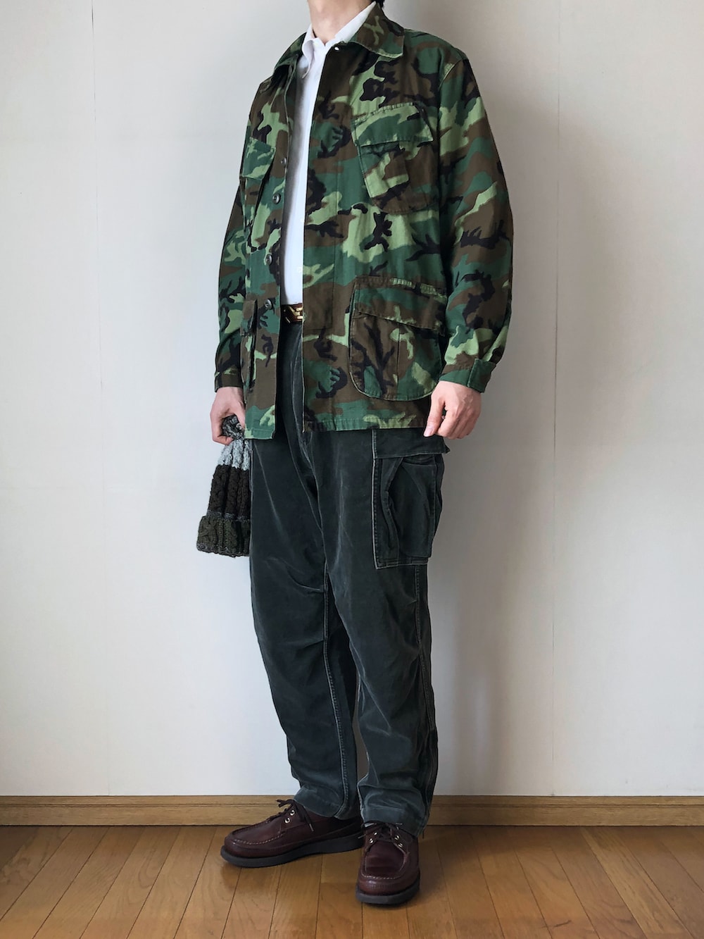「ジャングルファティーグ、JUNGLEFATIGUE、ミリタリー、ミリタリージャケット、カモフラ、ボタンダウンシャツ、白シャツ、タックイン、カーゴパンツ、ベロアパンツ、ニット帽、ポンポン帽子、ケーブルニット、モカシン、ブーツ」|「MILITARYのJUNGLE FATIGUE JACKET(ミリタリージャケット、グリーン系)」を使った、となりさん(メンズ・179cm)の春コーディネートの2枚目の写真