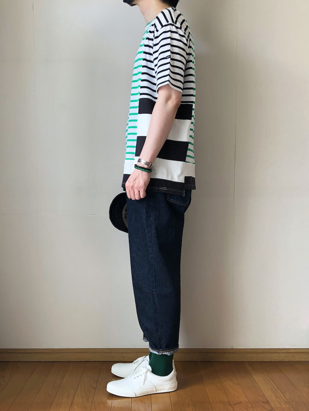 グリーン系のTシャツ/カットソー、ブルー系のデニムパンツ、ホワイト系のスニーカーを着用したメンズの夏コーディネートの3枚目の写真