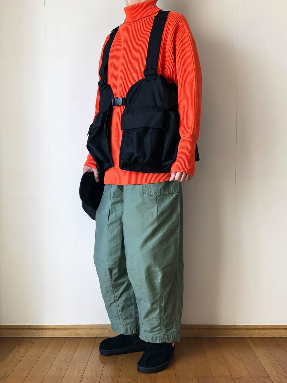 ブラック系のベスト、オレンジ系のニット/セーター、グリーン系のその他パンツを着用したメンズの冬コーディネートの2枚目の写真