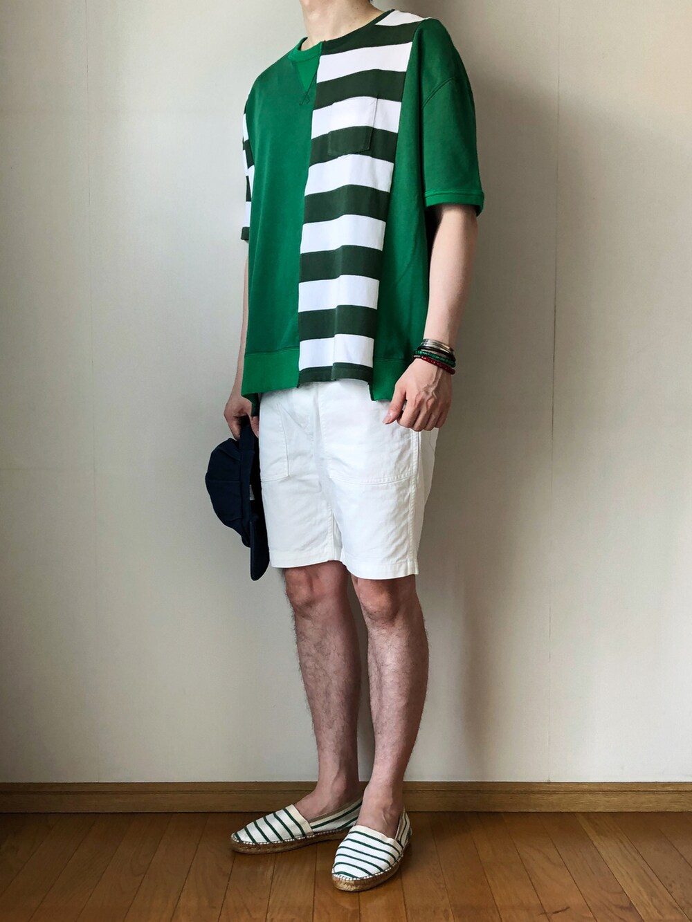 グリーン系のスウェット、ホワイト系のパンツ、グリーン系のスリッポンを着用したメンズの夏コーディネートの2枚目の写真