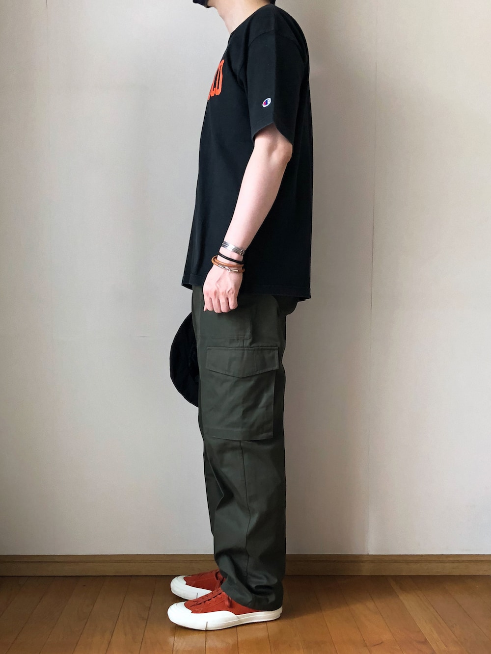 ブラック系のTシャツ/カットソー、グリーン系のカーゴパンツ、オレンジ系のスニーカーを着用したメンズの夏コーディネートの3枚目の写真
