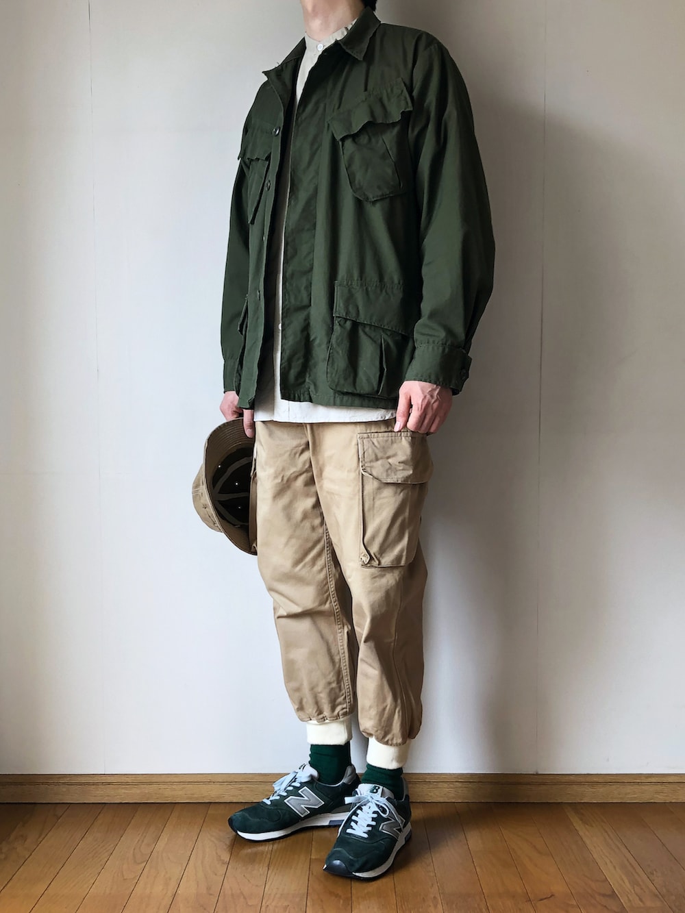 グリーン系のミリタリージャケット、ベージュ系のシャツ/ブラウス、ベージュ系のカーゴパンツを着用したメンズの春コーディネートの2枚目の写真