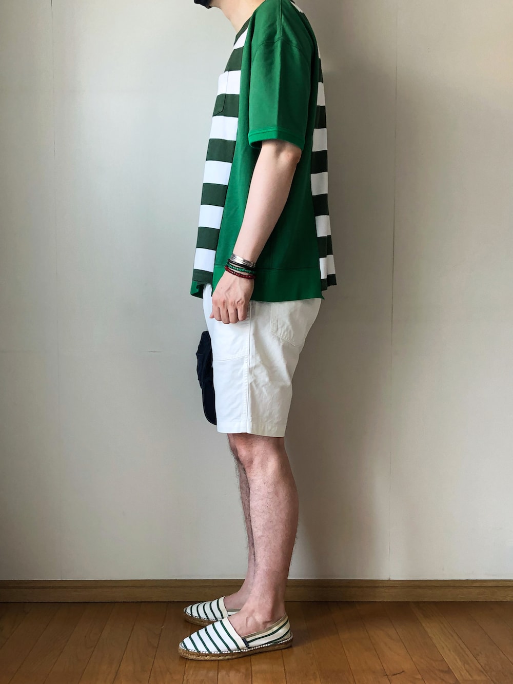 グリーン系のスウェット、ホワイト系のパンツ、グリーン系のスリッポンを着用したメンズの夏コーディネートの3枚目の写真