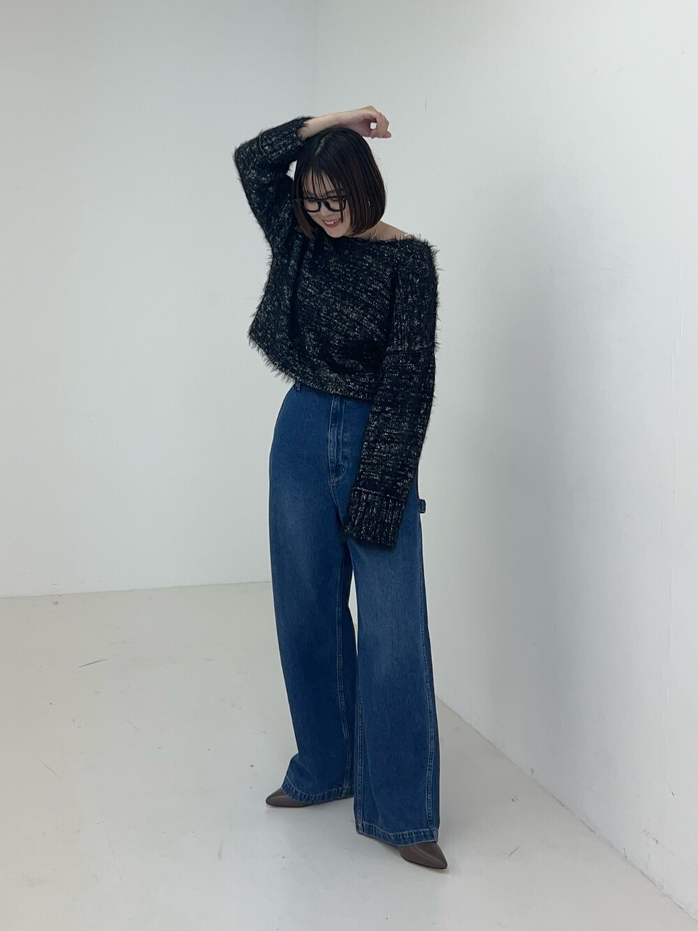 ブラック系のニット/セーター、ブルー系のデニムパンツを着用したレディースの秋コーディネートの2枚目の写真