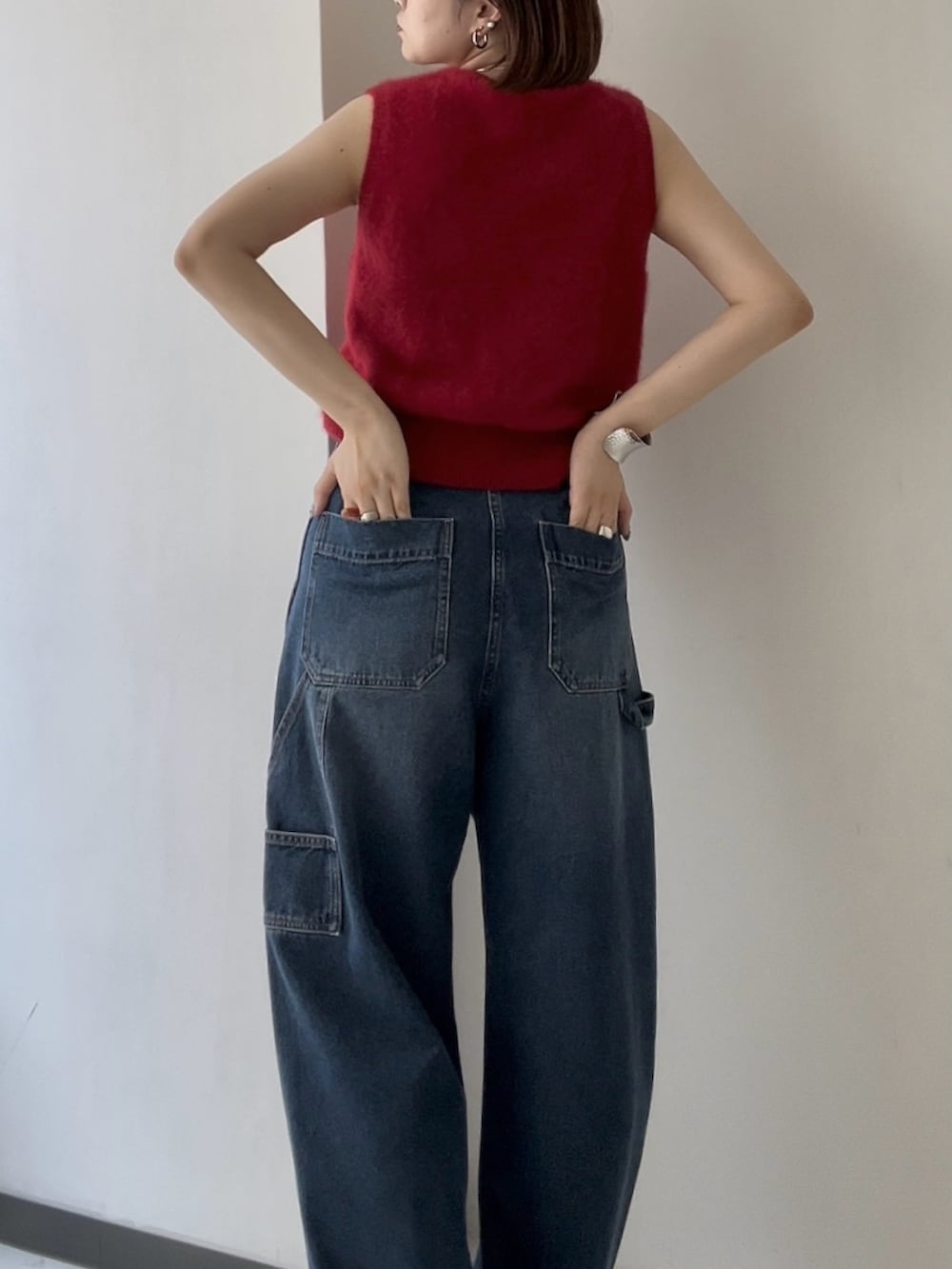 レッド系のベスト、ブルー系のデニムパンツを着用したレディースの夏コーディネートの3枚目の写真