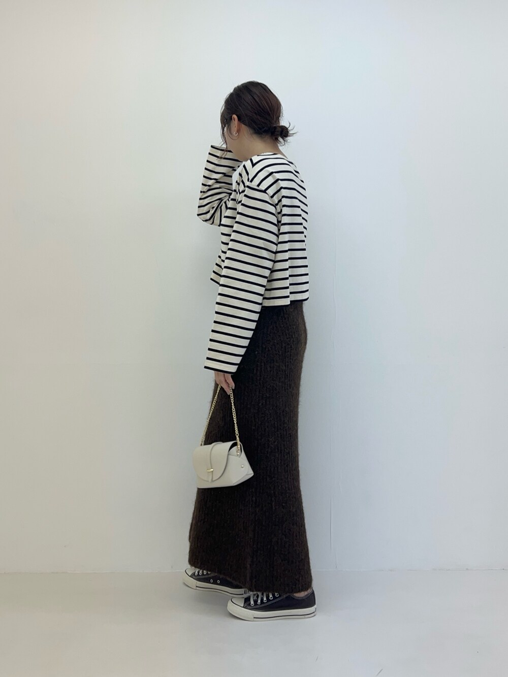 ブラウン系のスカート、ホワイト系のTシャツ/カットソー、ホワイト系のショルダーバッグを着用したレディースの冬コーディネートの2枚目の写真